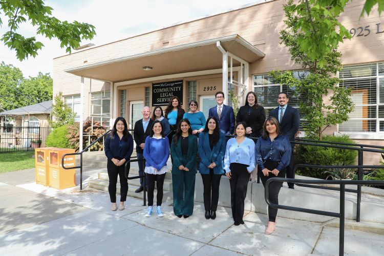 A group of 13 people pose for a photo outside of the clinic building